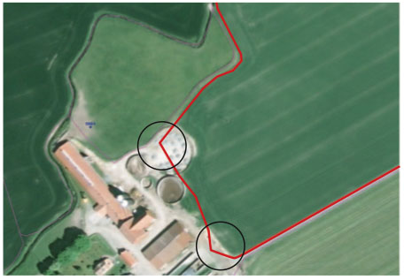 Flygfoto över gård. Blockets gränser är markerade med röd färg. Två cirklar visar var blockets gränser inte stämmer överens med verkligheten.