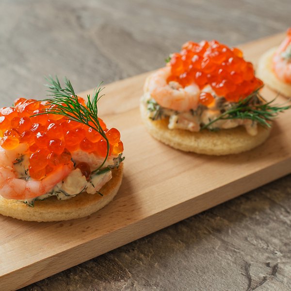 Toast skagen med räkor och rom på en bräda.